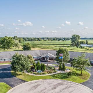 Aerial view of a motel surrounded by lush greenery and fields with a clear blue sky.