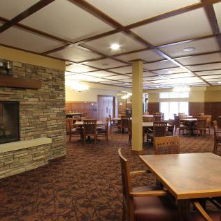 Spacious dining area with wooden furniture and a stone fireplace.