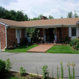 A suburban brick house with a driveway and well-maintained lawn.
