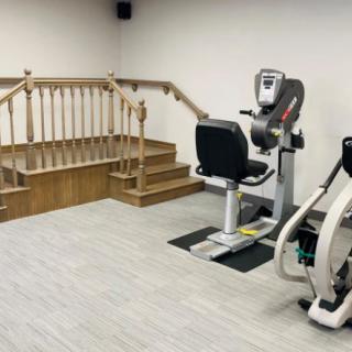 A physical therapy room with exercise equipment and a wooden staircase for rehabilitation exercises.