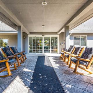 A covered patio with wooden rocking chairs arranged in rows, creating a cozy outdoor seating area.