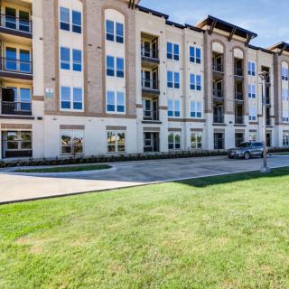 A modern residential apartment complex with a well-maintained lawn.