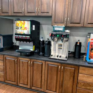 A beverage station featuring a soda machine and coffee dispensers in a kitchen setting.