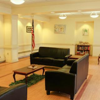 A cozy waiting area with black sofas and a coffee table, featuring an American flag.