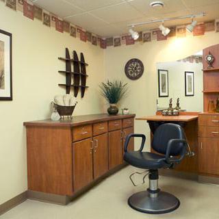 A cozy salon setup featuring a styling chair, mirror, and wooden cabinetry.