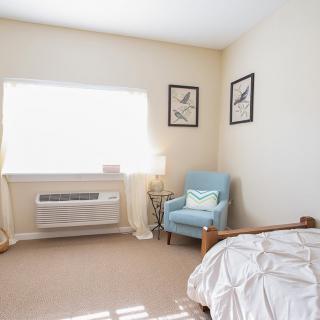A minimalist bedroom with a comfortable armchair and natural light.