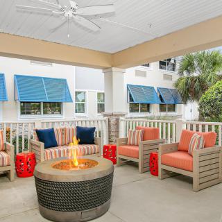 A cozy outdoor patio with comfortable seating and a fire pit under a covered area.