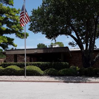 A view of a building with an American flag and well-maintained landscaping.