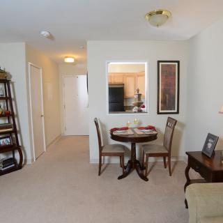 A cozy living room interior with a small dining area and a bookshelf.