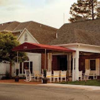 A charming residential building featuring a welcoming porch with rocking chairs.