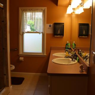 A warm-toned bathroom featuring a double sink vanity with mirrors and overhead lighting.