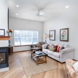 A cozy and well-lit living room featuring a sofa, coffee table, and a fireplace with elegant decor.