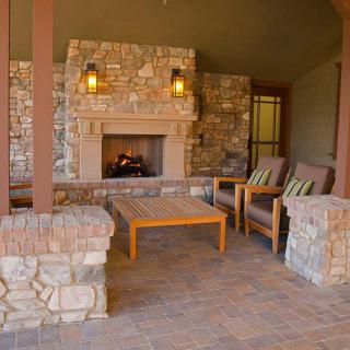 A cozy outdoor patio featuring a stone fireplace and comfortable seating.