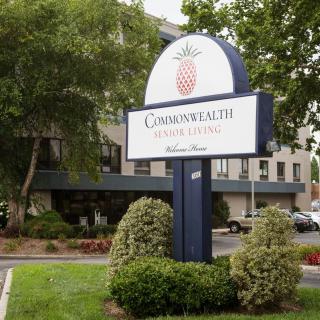 A sign for Commonwealth Senior Living stands amidst landscaped greenery in front of a multi-story building.