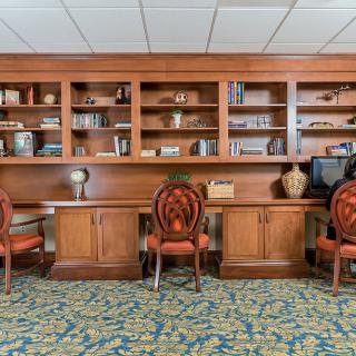 A cozy library space with wooden bookshelves, decorative items, and chairs.