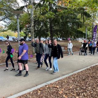 A group of people participating in a community walk along a tree-lined path.
