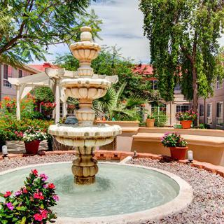 A beautiful garden setting with a multi-tiered fountain surrounded by lush greenery and vibrant flowers.