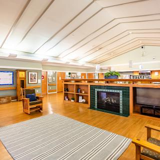 A spacious living room with a modern architectural design featuring wooden furniture, a fireplace, and built-in bookshelves.