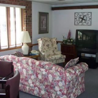 A cozy living room featuring a floral couch, armchair, television, and table lamp.