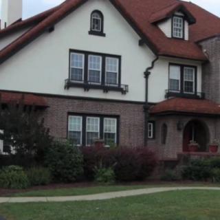 A two-story residential house with a red roof and a well-maintained garden.
