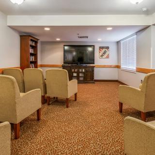 A cozy conference room with arranged seating facing a large television.