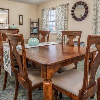 A cozy dining room featuring a wooden table with matching chairs, adorned with elegant home decor and curtains.