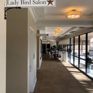 A corridor leading to the Lady Bird Salon, with large windows allowing natural light.