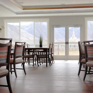A spacious dining area with wooden furniture and large windows offering a view of the mountains.