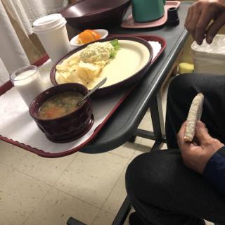 A hospital meal served on a tray, featuring soup, mashed potatoes, vegetables, and drinks.