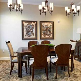 A cozy dining room featuring a wooden table and chairs, adorned with elegant chandeliers and decorative artwork on the walls.