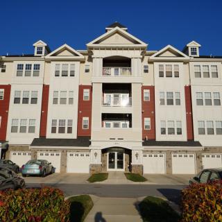 A multi-story apartment building with a symmetrical design and multiple garage doors.