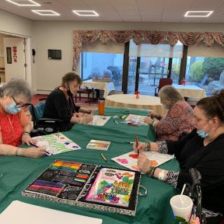 A group of older adults engaged in a painting session, showcasing their creativity and enjoying a social activity.