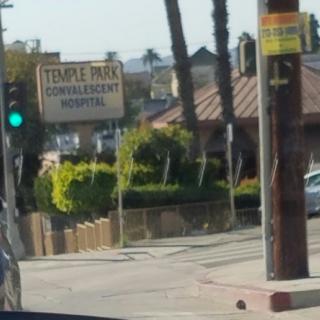 View of a hospital sign at an intersection, with a green traffic light visible.