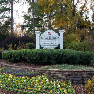 Entrance sign surrounded by lush greenery and colorful flowers.