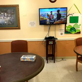 A view of a common area featuring a television, tables, and chairs.