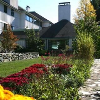A scenic view of a landscaped garden with vibrant flowers and a stone pathway leading towards a modern building.