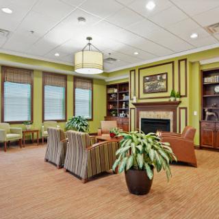 A cozy lounge area featuring comfortable seating, a fireplace, and vibrant green walls.