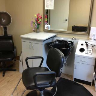 A cozy hair salon with a barber chair, sink, and mirror.