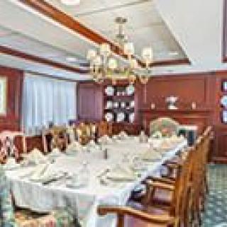 An elegant dining room with a large table set for a formal meal, featuring a chandelier and classic decor.