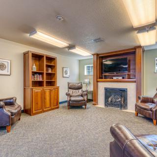 A cozy living room with leather seating, a fireplace, and a wooden bookshelf.