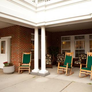 A cozy porch area with rocking chairs in front of a brick building.