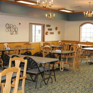 An empty dining room with tables and chairs, decorated with wall art.