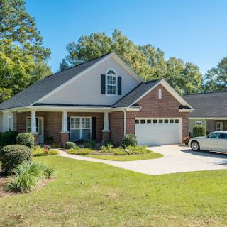 A charming residential house with a well-maintained lawn and driveway.