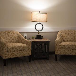 A cozy seating area with two patterned chairs, a central table, and a lamp providing warm lighting.
