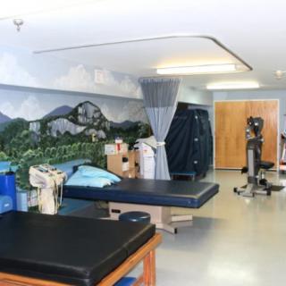 A rehabilitation room equipped with treatment tables and exercise equipment, designed for physical therapy sessions.