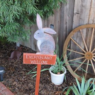 A garden scene with a wooden bunny, a sign reading 'EVERGREEN VILLAGE', plants, and a wagon wheel.