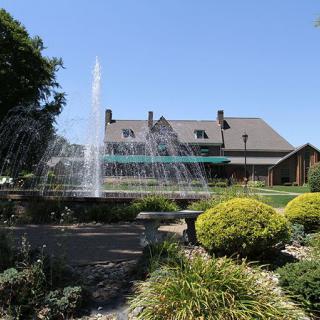 A beautiful garden with a large fountain in front of a rustic building.