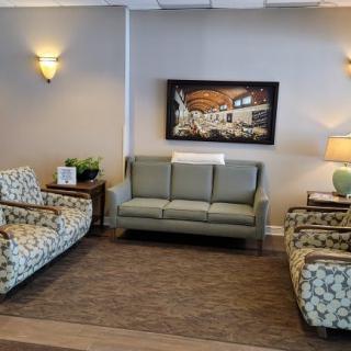 A cozy living room setup with a sofa, patterned chairs, and wall artwork.