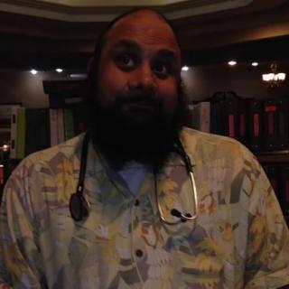 A person with a beard wearing a stethoscope indoors.