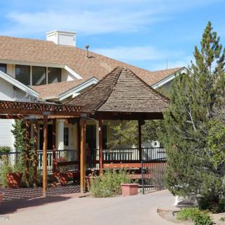 A charming house with a wooden gazebo and surrounding trees.